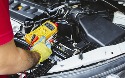 A mechanic holding a digital multimeter to check the car
